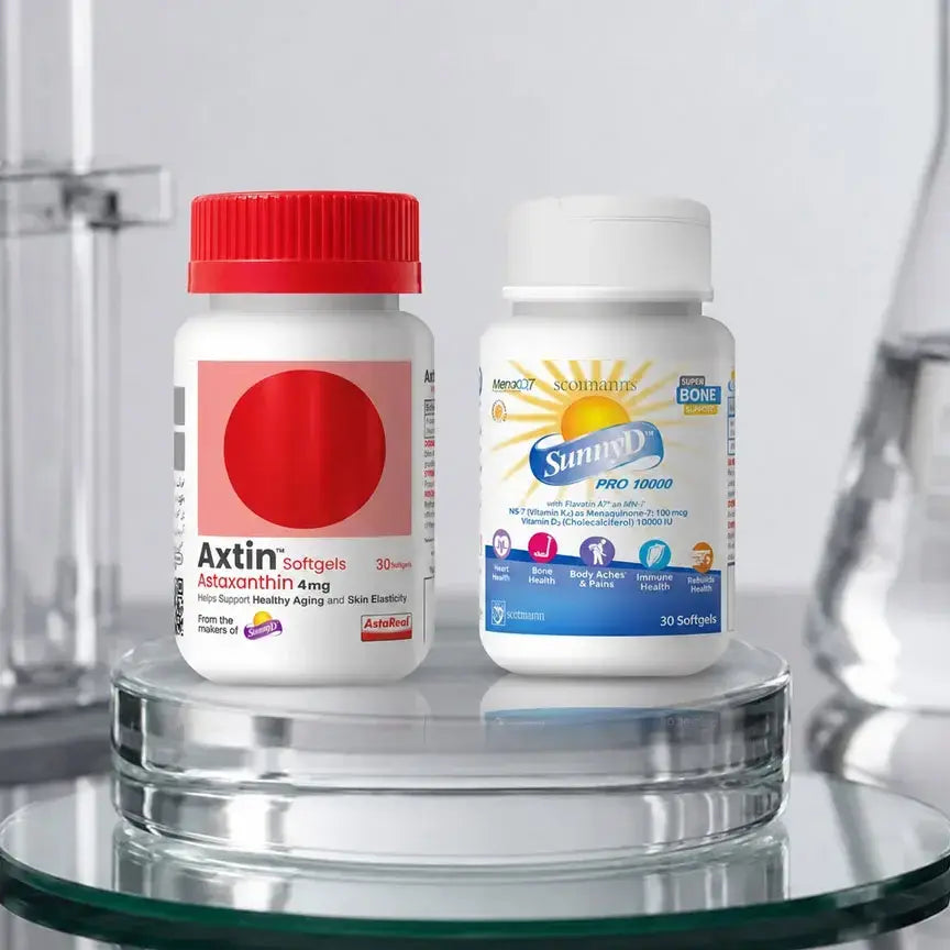 Two supplement bottles displayed on a glass pedestal: Axtin softgels with a red cap and white bottle, and Sunny Day Pro 10000 with a blue and white label and white cap, set against a softly blurred laboratory-style background.