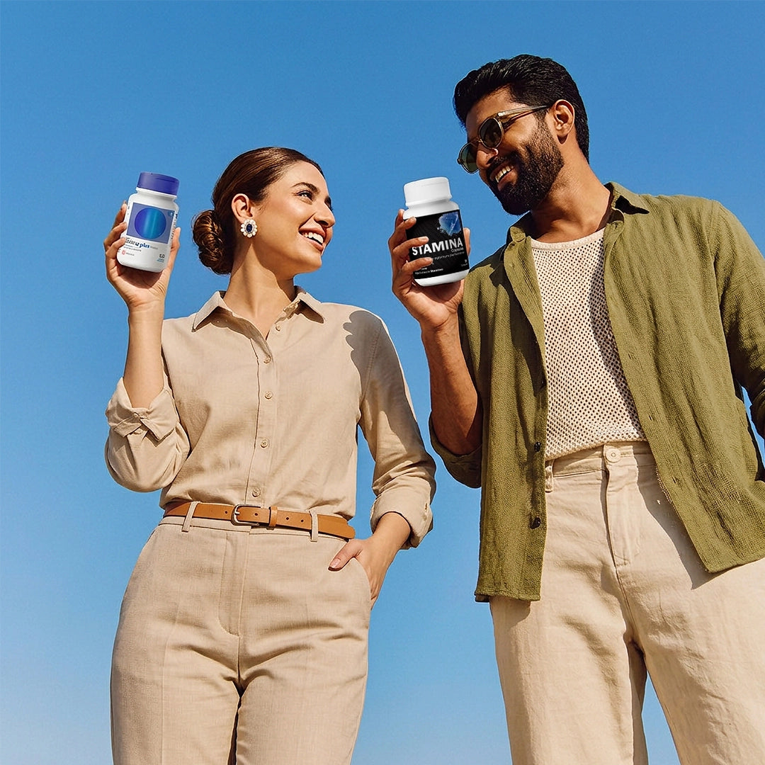 Man and woman holding bottles of Stamina supplements against a clear blue sky