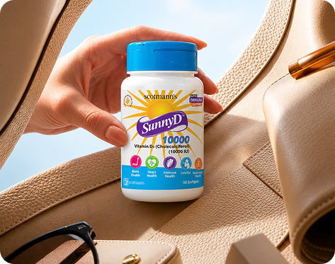 A hand holds a bottle of SunnyD 10000 Vitamin D3 supplements against a background of a beige leather handbag and a blue sky.